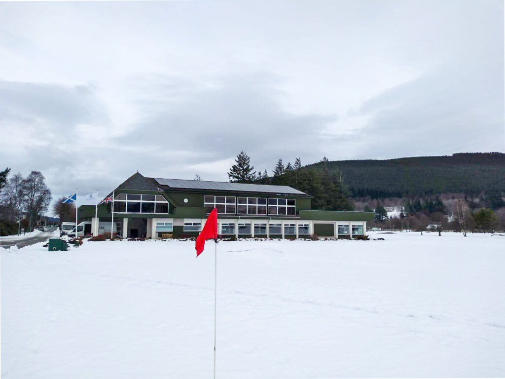 Golf club in a snowy backdrop with red golf flag in foreground