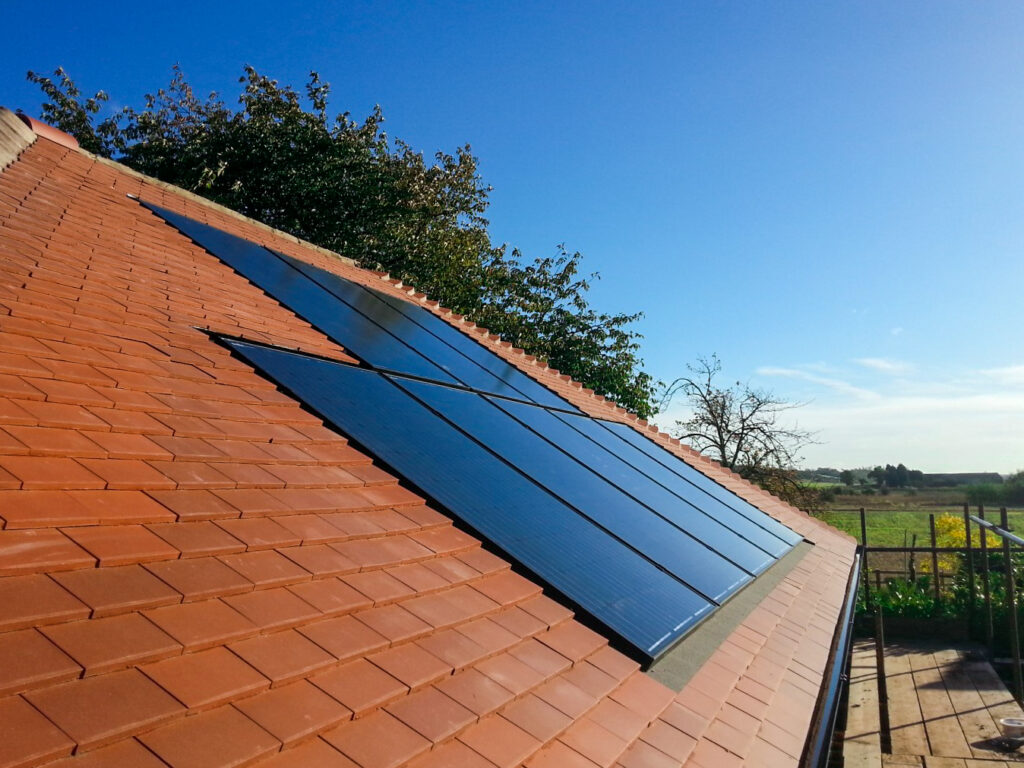 Orange tiled roof with 8 solar panels and blue sky