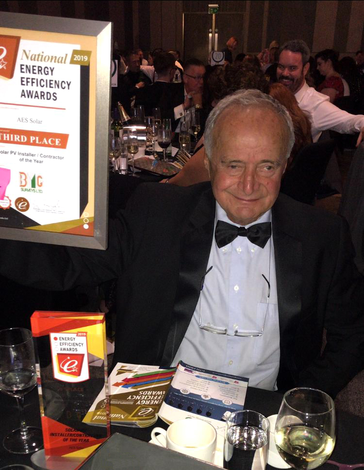 Man in suit holding trophy and certificate
