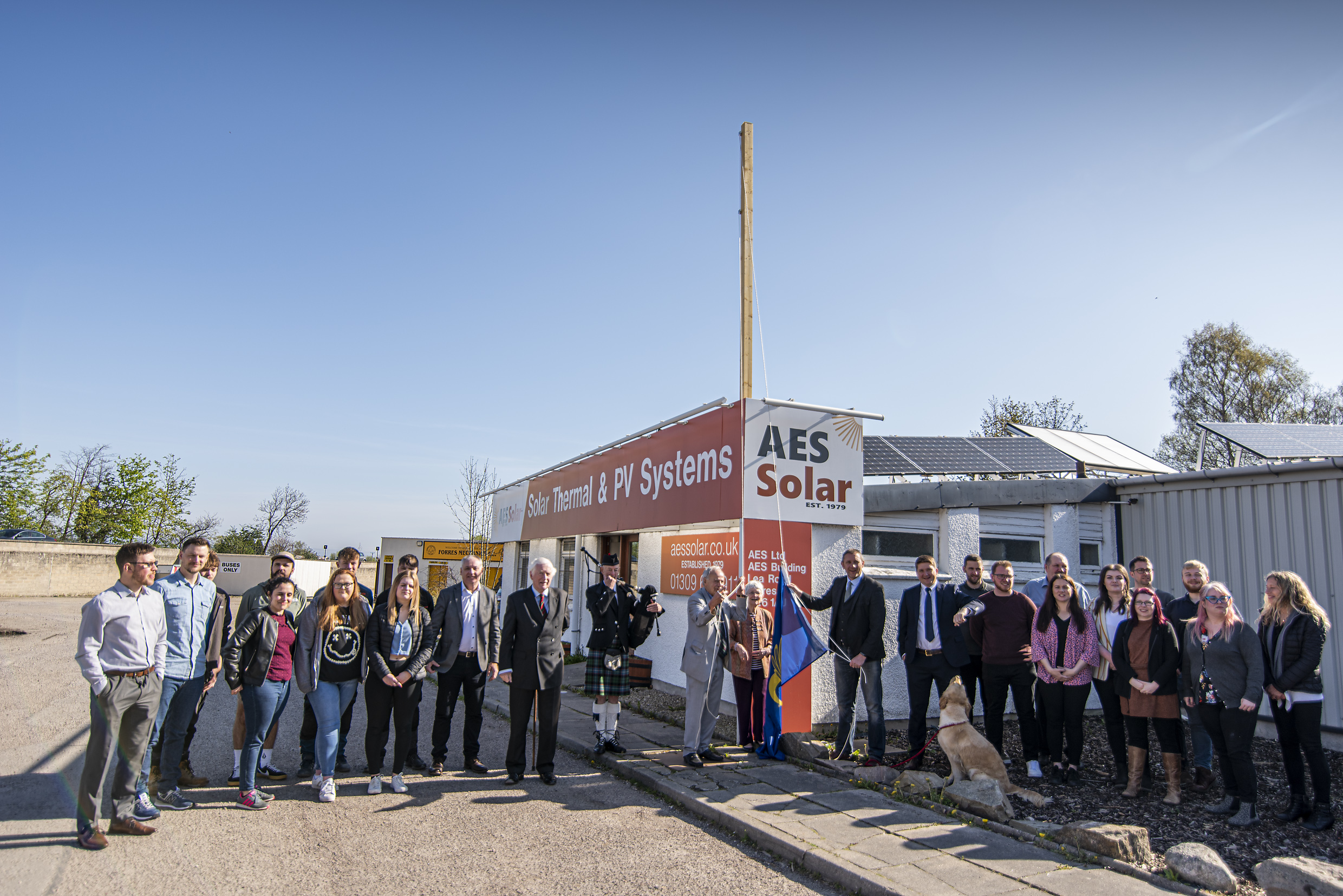 AES Solar celebrate queen's award win by hoisting the Queen's Award flag.