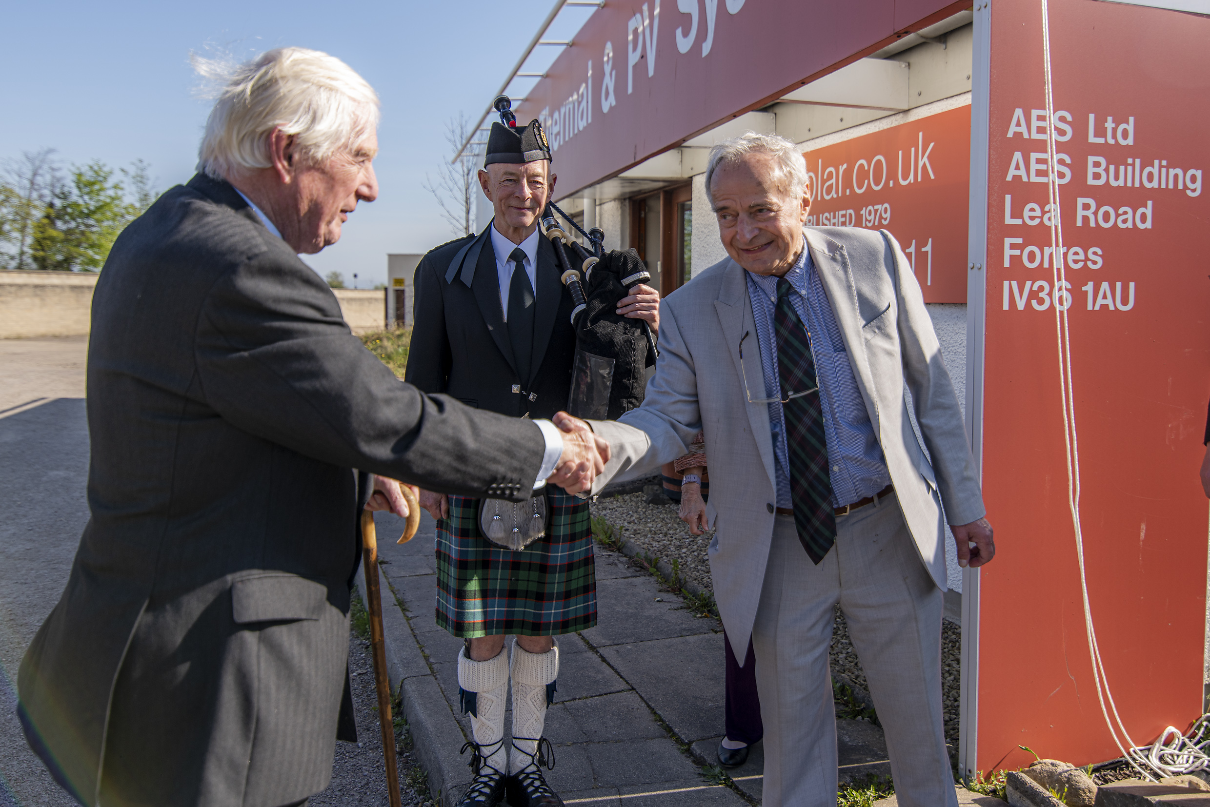 George celebrates the queen's award win with Lord Lieutenant Seymour Monro while a piper looks on.