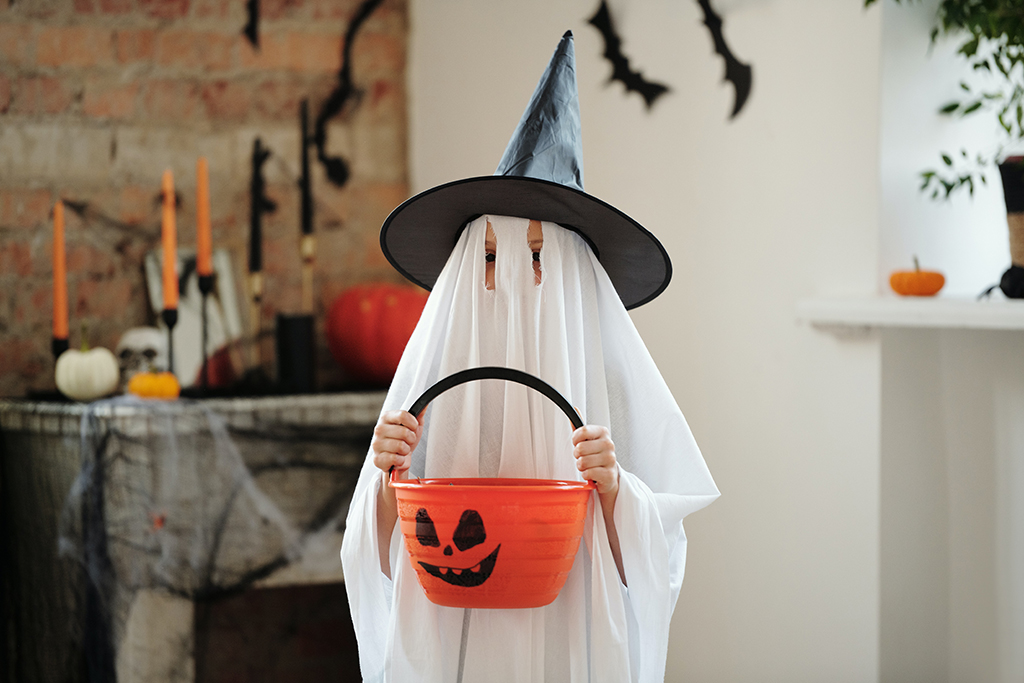 child dressed in a homemade ghost costume for a Sustainable Halloween 2022.